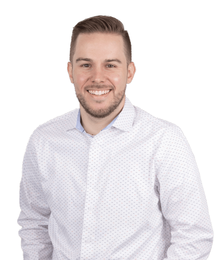 A man with short brown hair and a beard, wearing a white button-up shirt with small blue patterns, smiles while standing against a plain white background.