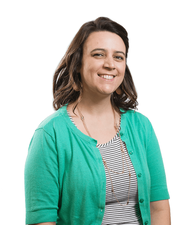 A woman with shoulder-length brown hair smiles at the camera. She is wearing a green cardigan over a black-and-white striped shirt and a long necklace. The background is plain white.