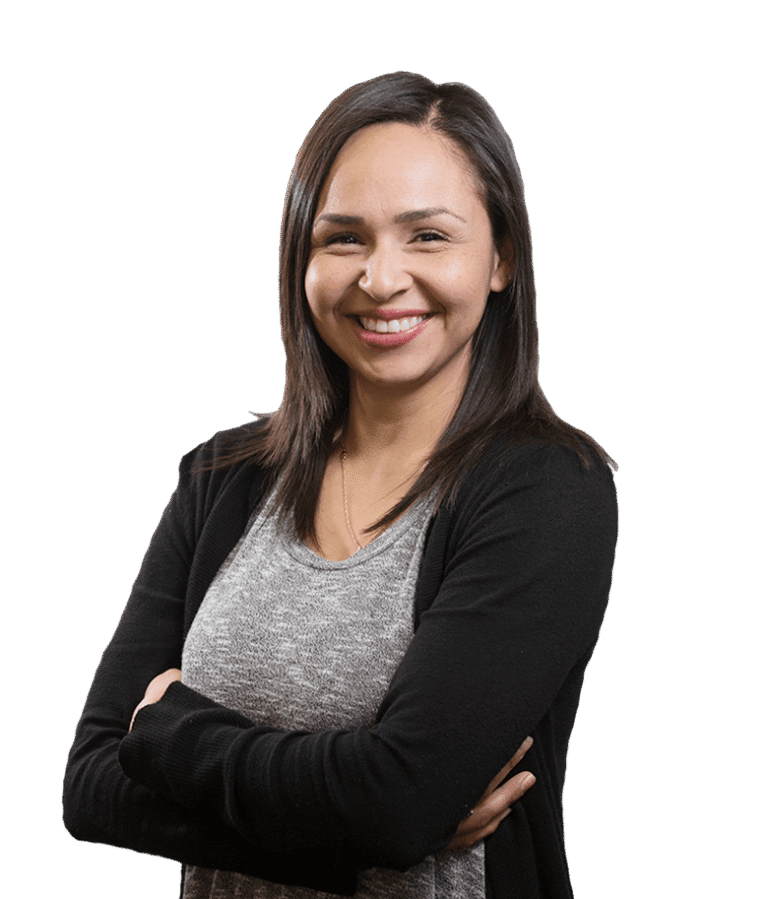 A woman with straight dark hair, wearing a grey shirt and black cardigan, smiles with her arms crossed against a plain white background.