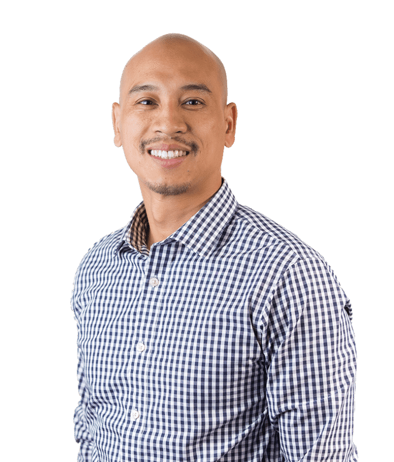 A smiling man with a shaved head wearing a blue and white checkered shirt, standing against a plain white background.