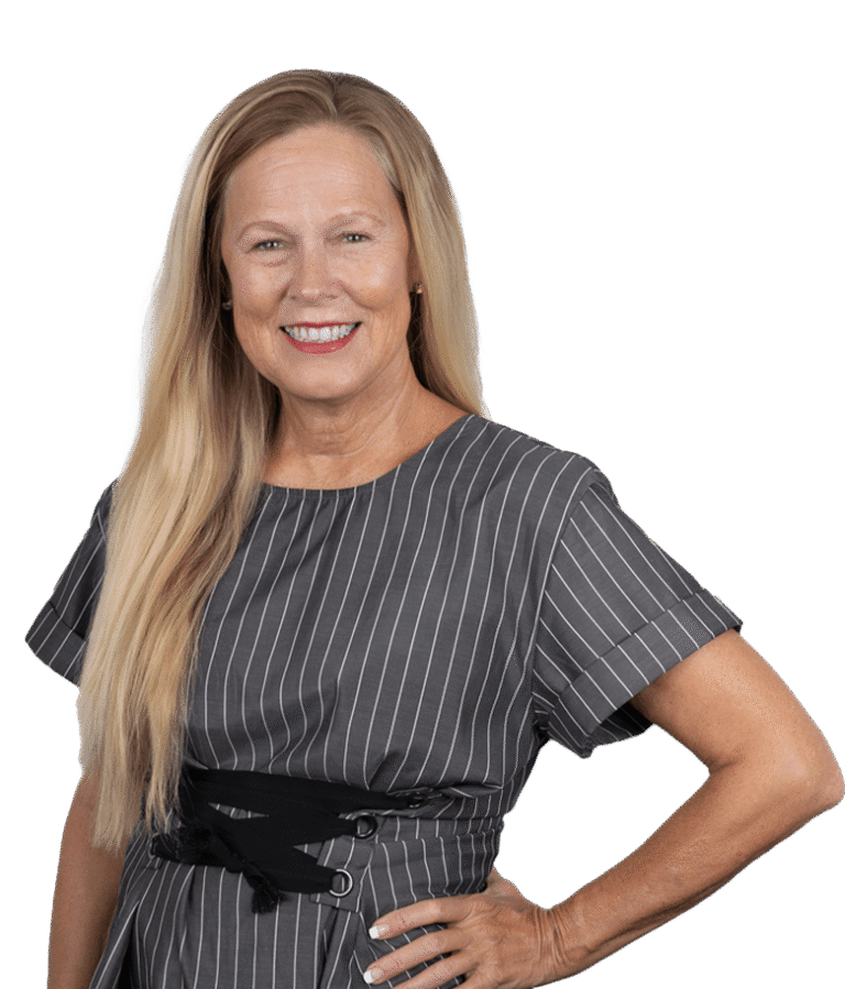 A smiling woman with long blonde hair wearing a gray dress with white pinstripes stands with one hand on her hip against a plain white background.