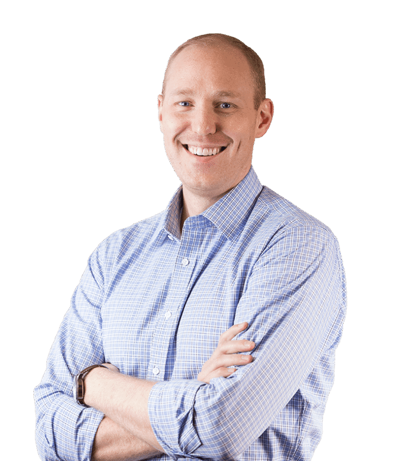A smiling man with short hair, wearing a light blue checkered shirt, stands with arms crossed against a plain white background.