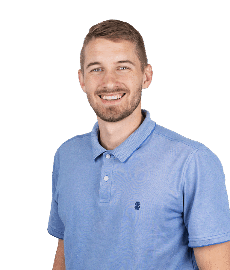 A smiling man with short light brown hair and a trimmed beard wears a light blue polo shirt and stands against a plain white background.