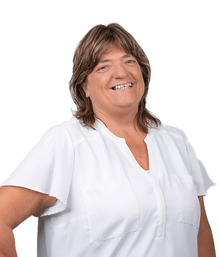 A person with shoulder-length brown hair, wearing a white short-sleeved shirt, smiling and standing against a plain white background.