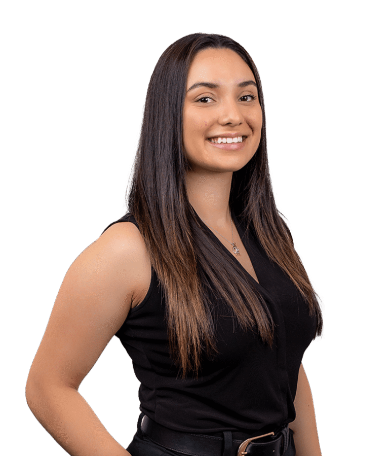 A woman with long straight brown hair, wearing a sleeveless black top, smiles while standing against a plain white background.