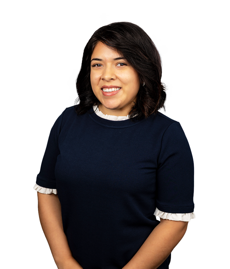 A woman with shoulder-length dark hair, wearing a navy blue top with white ruffled sleeves, smiles at the camera against a plain white background.