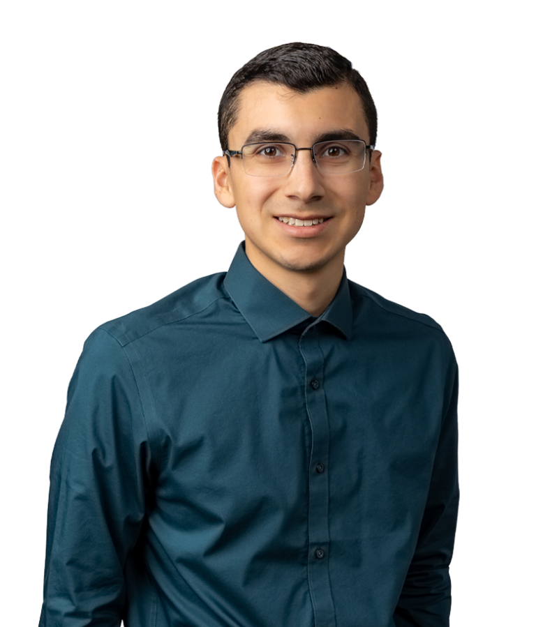A young man with short dark hair and glasses, wearing a teal button-up shirt, stands against a plain white background and smiles at the camera.