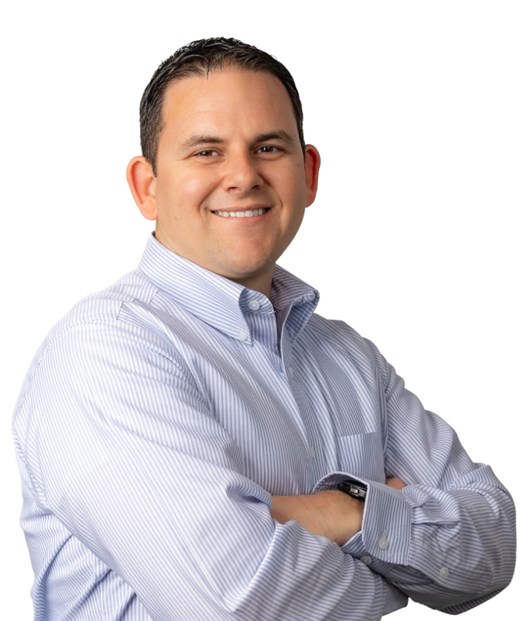A man with short dark hair, wearing a light blue striped button-up shirt, stands with his arms crossed and smiles at the camera against a plain white background.